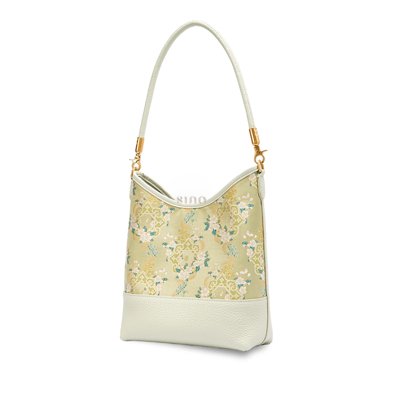 Angled view of a Chinoiserie Ruyi Blossom shoulder bag crafted from Song Brocade and pale green leather.