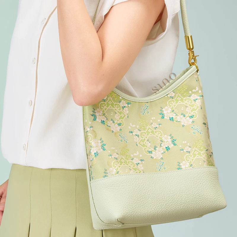 Model carrying the pale green Ruyi Blossom leather shoulder bag under the arm.