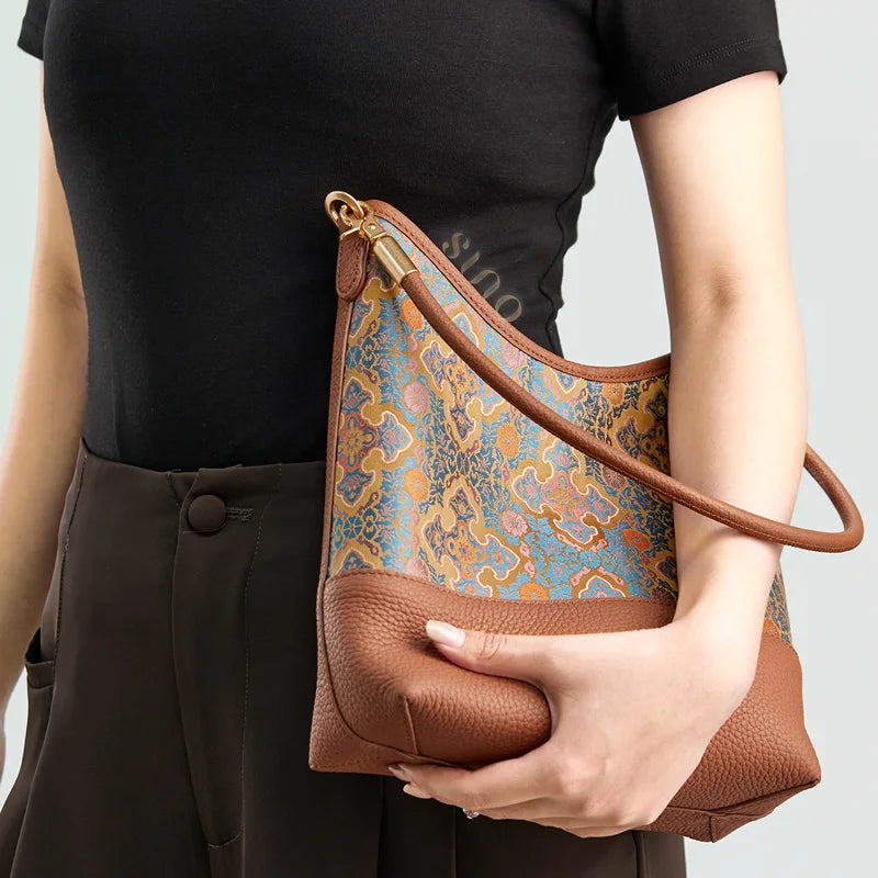 Model holding the Song Brocade Ruyi Motif leather shoulder bag with a modern black outfit.
