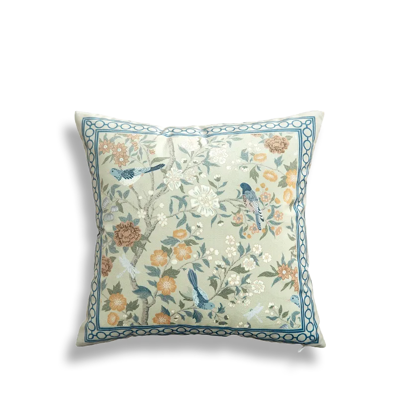 White embroidered pillow featuring full floral and bird scene.