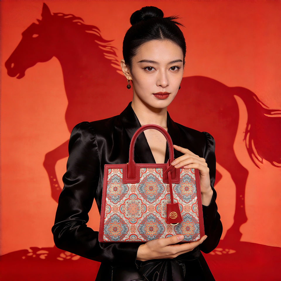 Model holding a luxury Year of the Horse brocade handbag with red leather accents, against a vibrant red background with a horse silhouette.