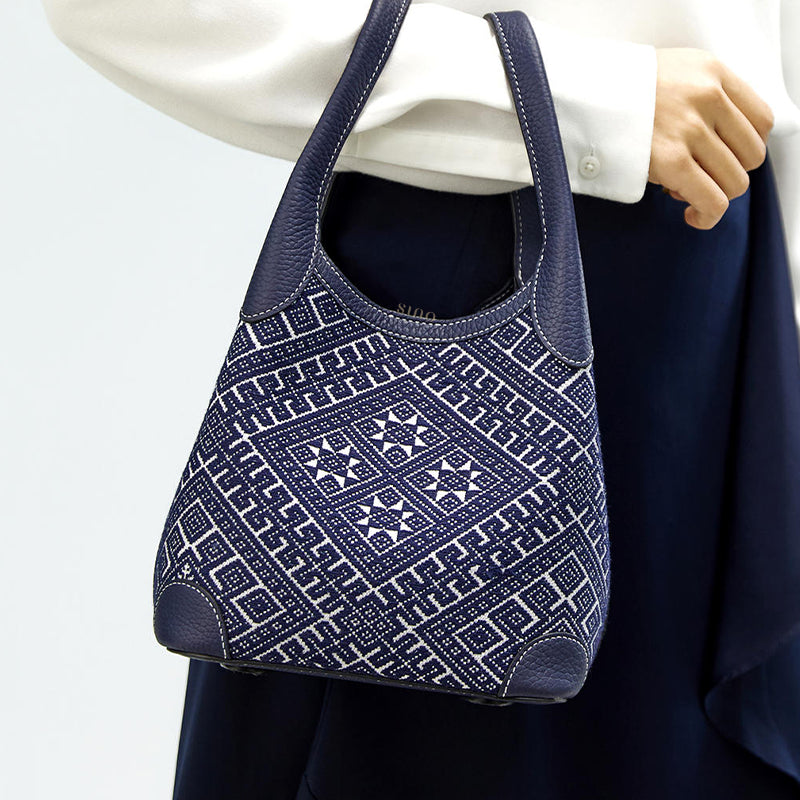 Luxury Zhuang brocade basket tote bag carried on model hand, side view styling, showing leather handles and daily outfit pairing.