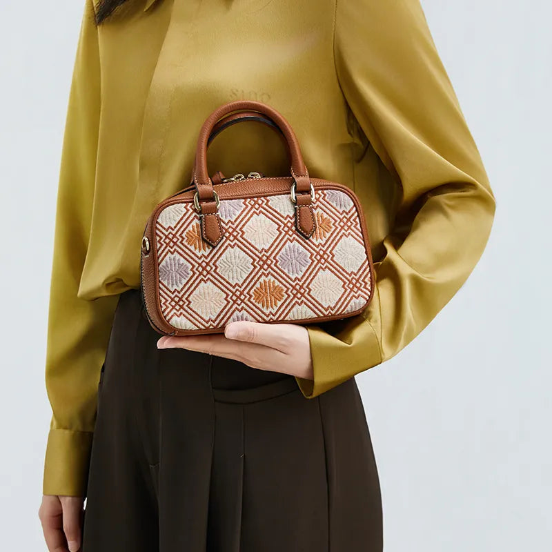 Model cradling lightweight Boston bag at chest level.