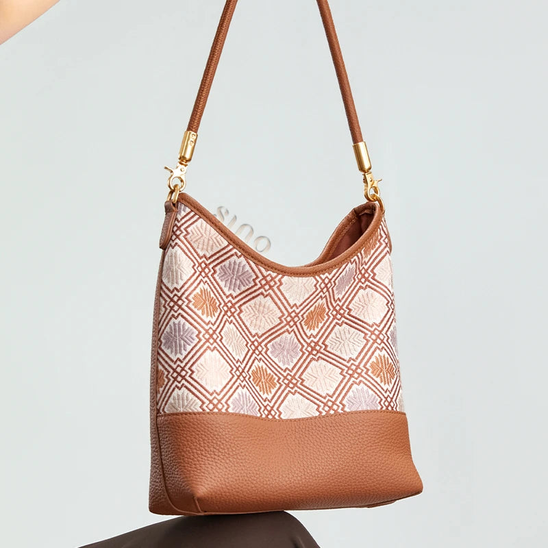 Model displaying the Chinoiserie Chrysanthemum Meander leather shoulder bag with its woven geometric floral pattern.