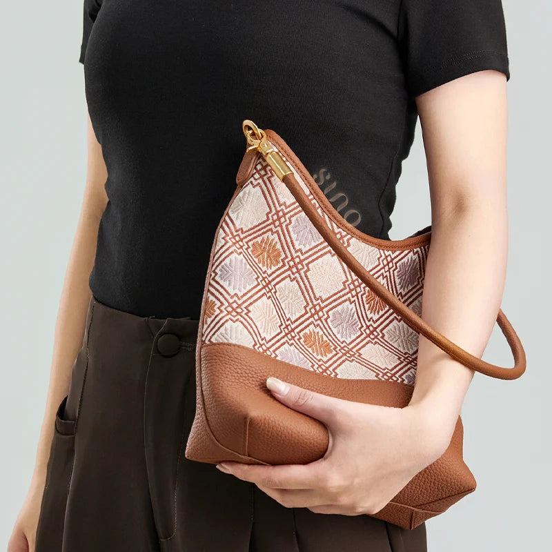 Model holding the Zhuang Brocade Chrysanthemum Meander leather shoulder bag with a modern black outfit.